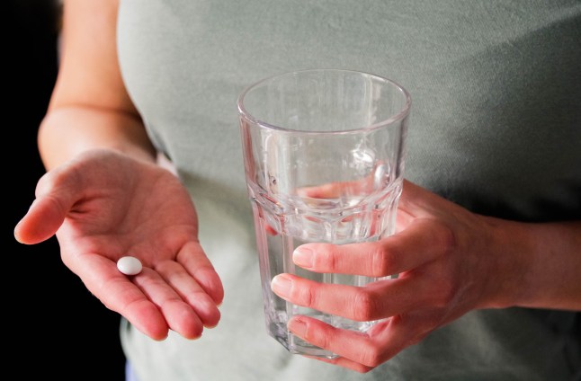 Woman taking painkiller with a glass of water.