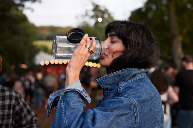Woman drinking water from a bottle at a festival.
