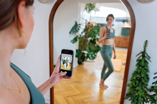 A young woman takes a selfie in the mirror in sportswear while preparing for exercise