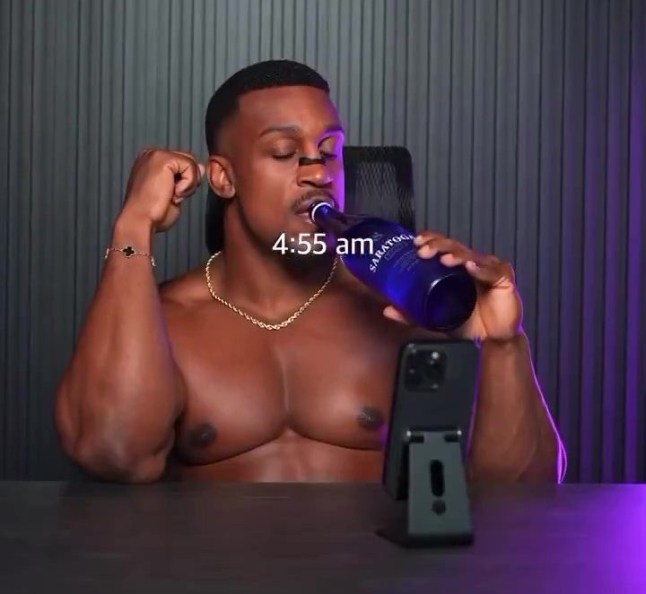 Ashton Hall drinking water and scrolling on his phone.