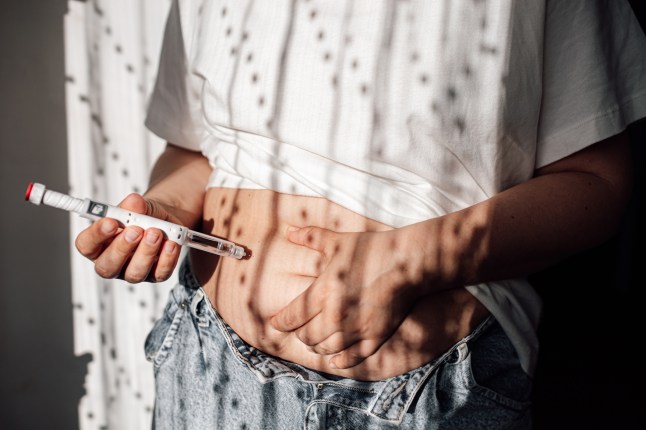 A woman gives herself an injection of semaglutide into the abdomen with a pen syringe.