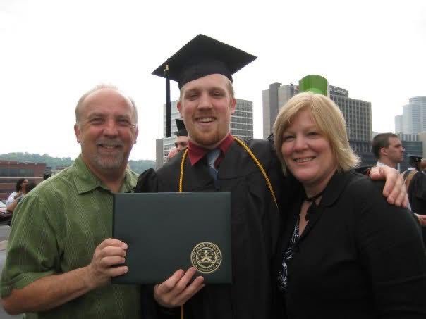 Kevin James Doyle wears graduation cap and gown while flanked by his parents